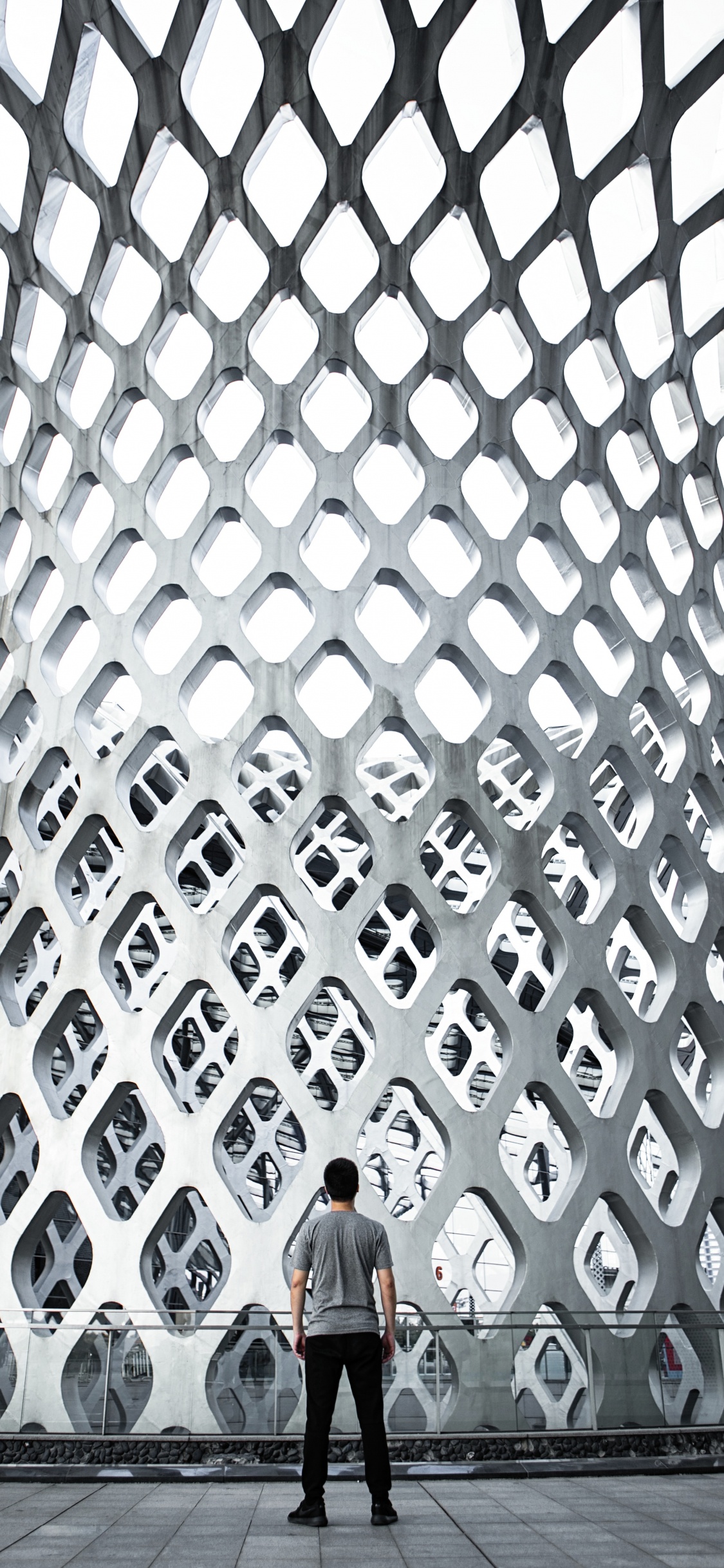 Frau in Schwarzer Jacke Steht Auf Grauem Betongebäude. Wallpaper in 1125x2436 Resolution