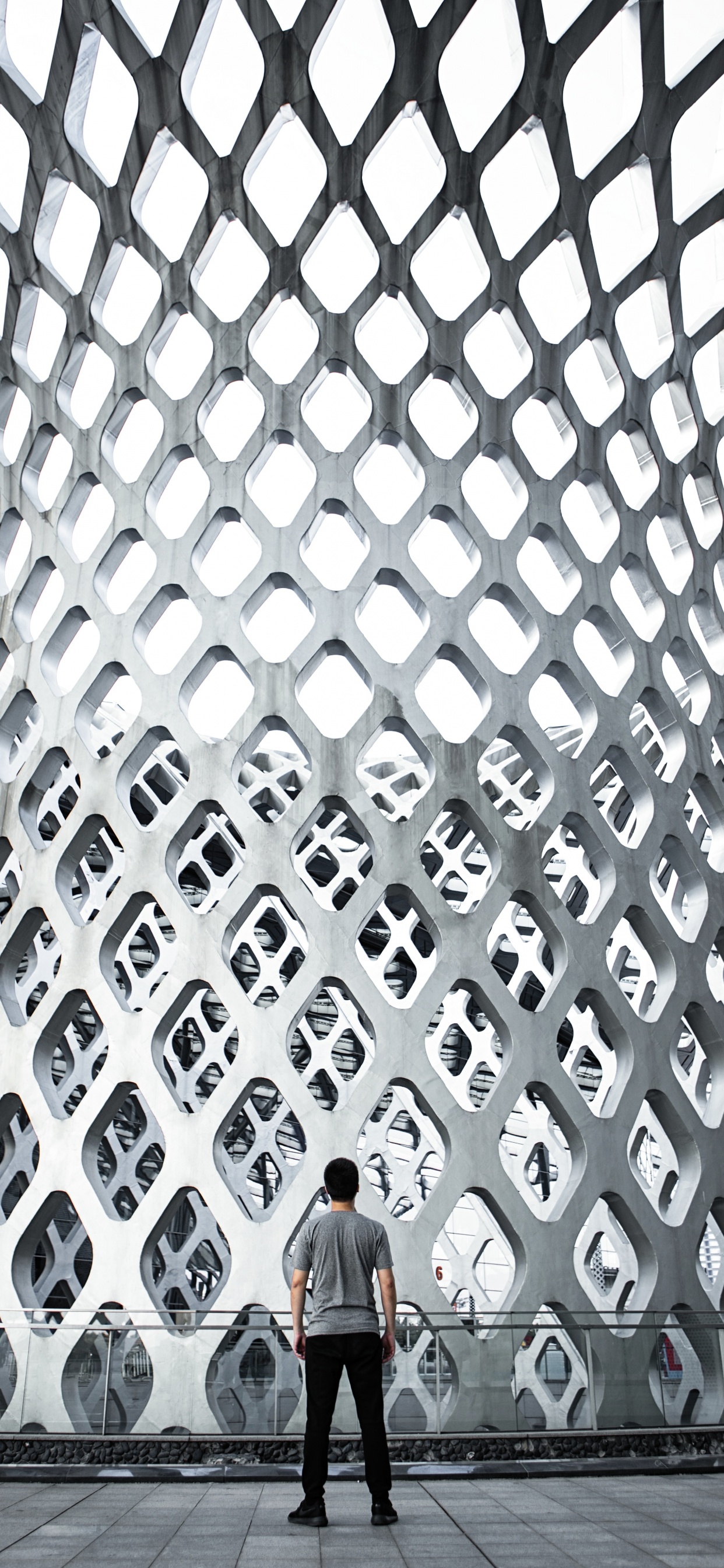 Frau in Schwarzer Jacke Steht Auf Grauem Betongebäude. Wallpaper in 1242x2688 Resolution