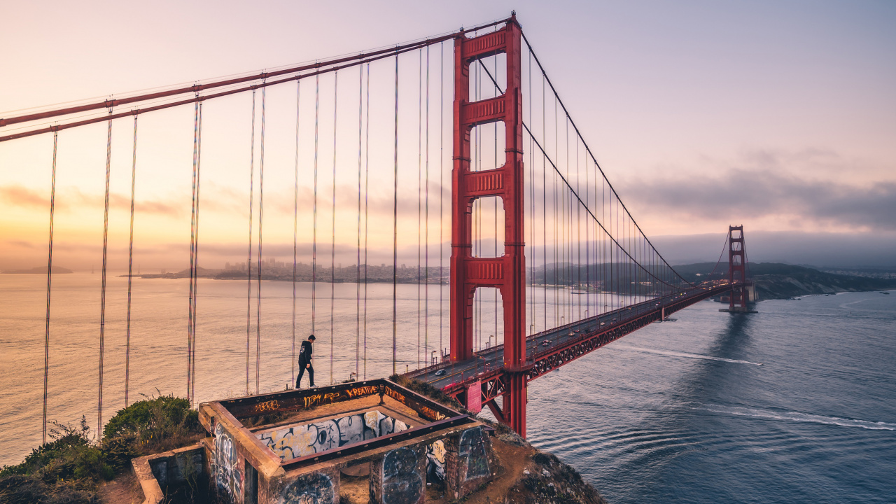 Man in Black Jacket Standing on Rock Near Golden Gate Bridge During Daytime. Wallpaper in 1280x720 Resolution