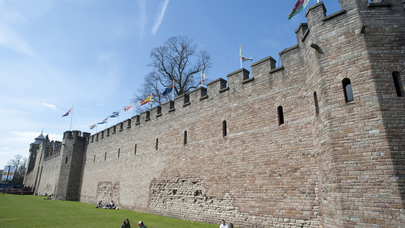 People Walking on Green Grass Field Near Brown Concrete Building During Daytime. Wallpaper in 1366x768 Resolution