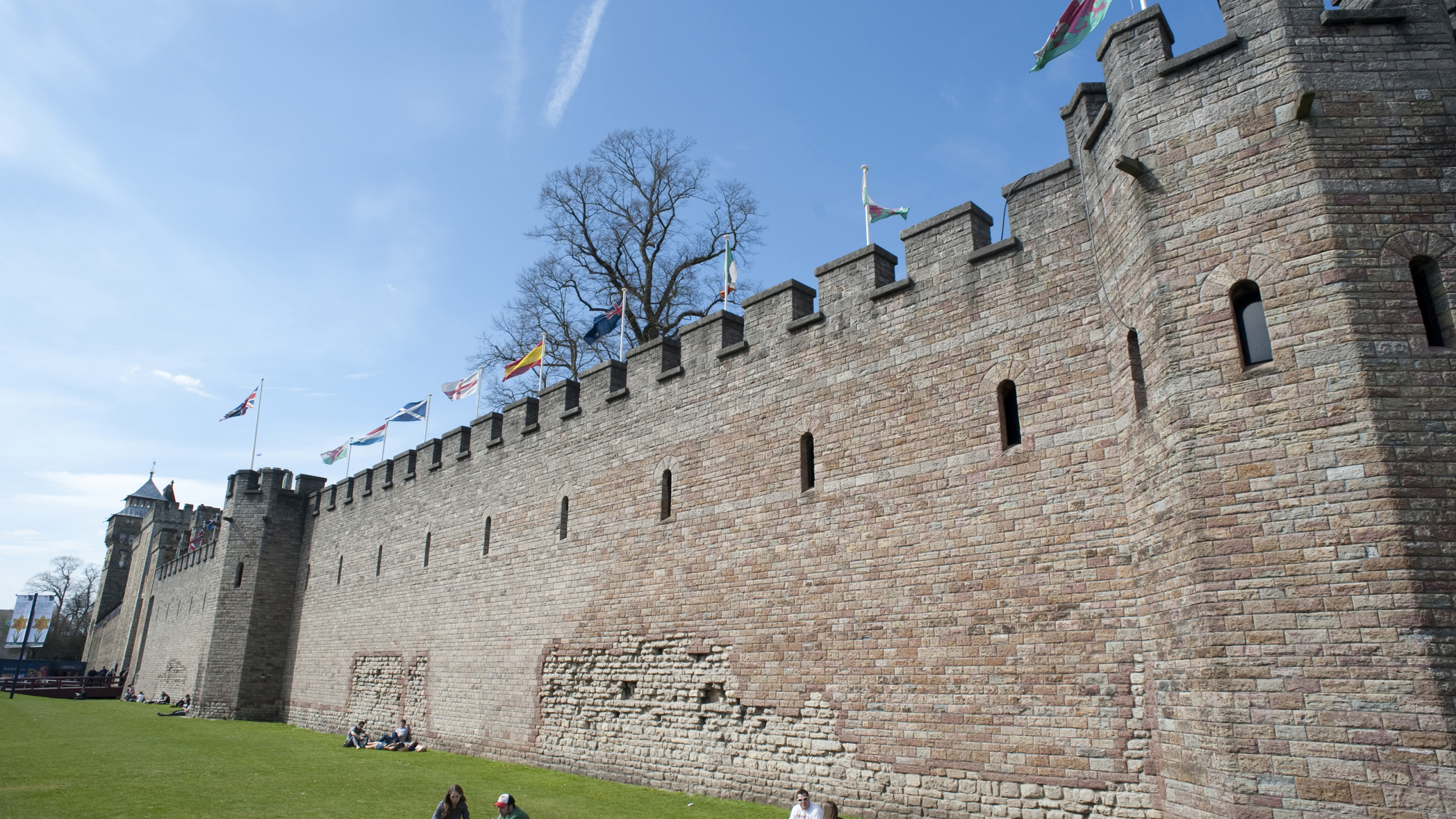 Menschen, Die Tagsüber Auf Einer Grünen Wiese in Der Nähe Eines Braunen Betongebäudes Gehen. Wallpaper in 2560x1440 Resolution