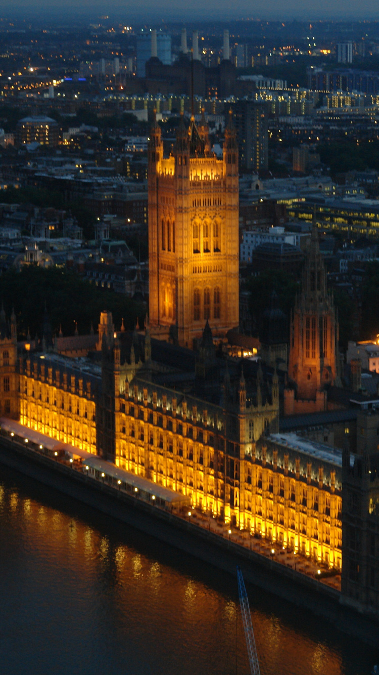 Brown Concrete Building Near Body of Water During Night Time. Wallpaper in 750x1334 Resolution