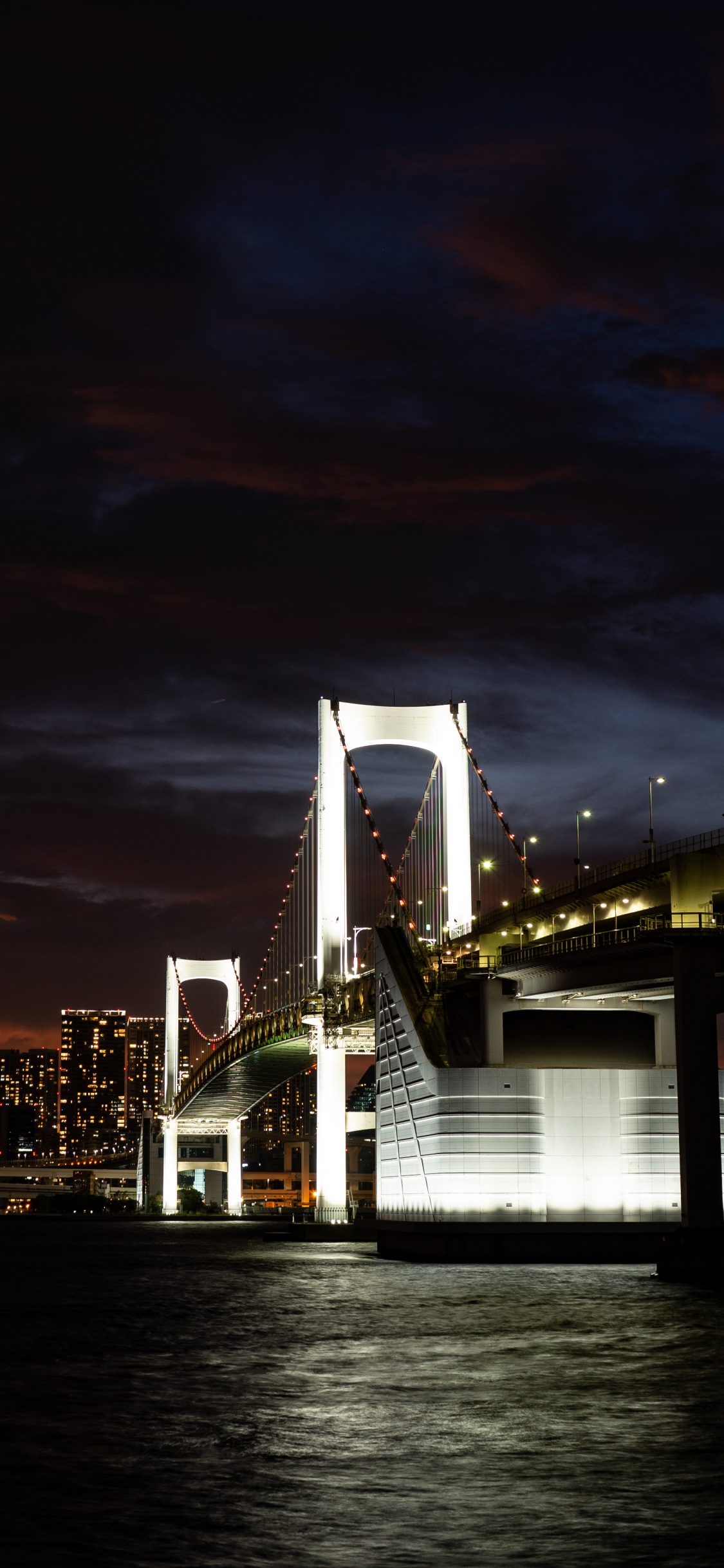 Bridge Over Water During Night Time. Wallpaper in 1125x2436 Resolution