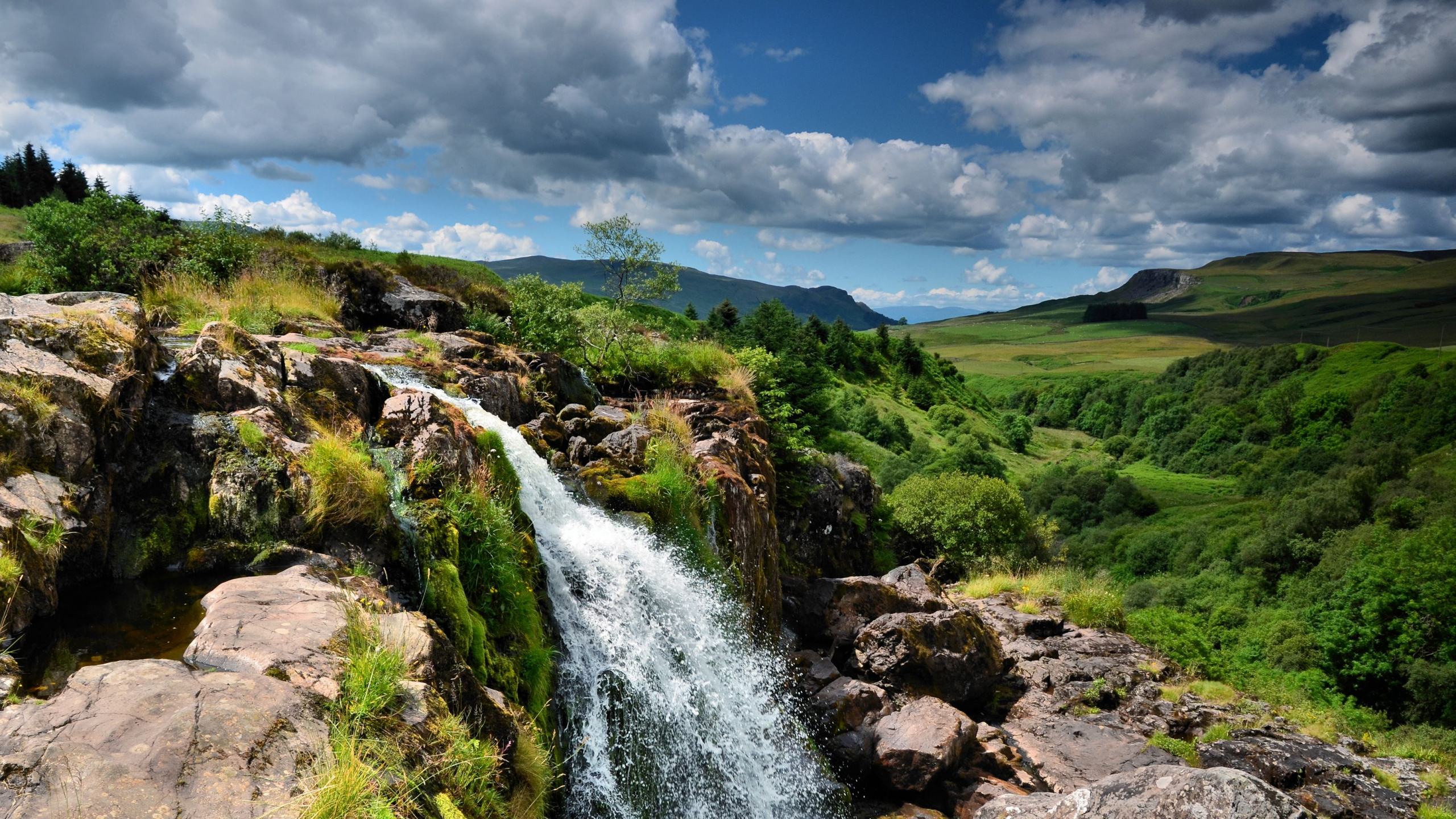 L'eau Tombe Sur le Champ D'herbe Verte Sous Les Nuages Blancs et le Ciel Bleu Pendant la Journée. Wallpaper in 2560x1440 Resolution