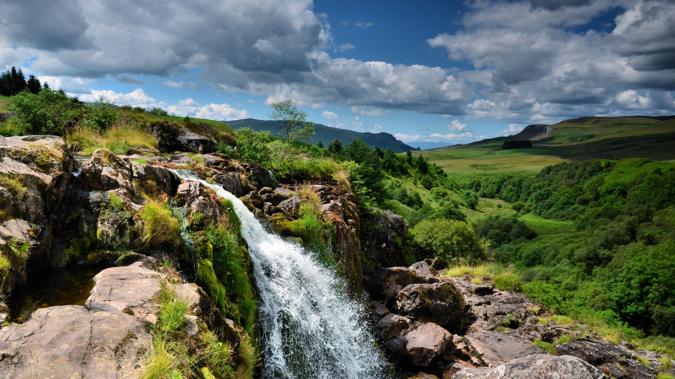 El Agua Cae Sobre el Campo de Hierba Verde Bajo Las Nubes Blancas y el Cielo Azul Durante el Día. Wallpaper in 1366x768 Resolution