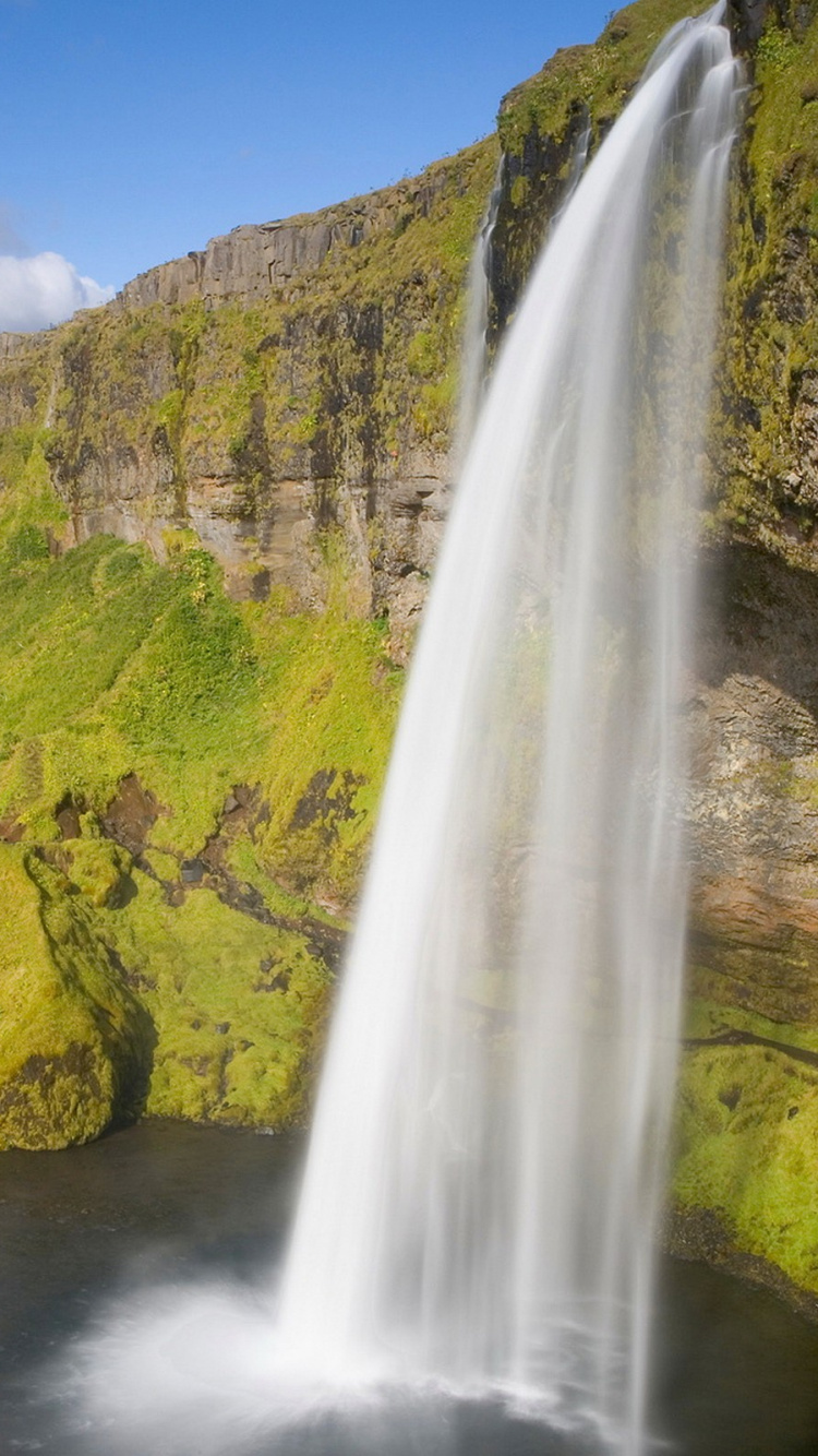 Wasserfälle Auf Grünem Gras Bedeckten Hügel Unter Blauem Himmel Tagsüber. Wallpaper in 750x1334 Resolution