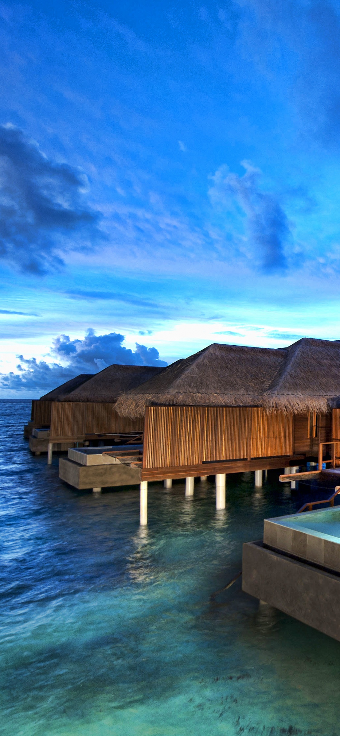 Brown Wooden Houses on Green Water Under Blue Sky During Daytime. Wallpaper in 1125x2436 Resolution