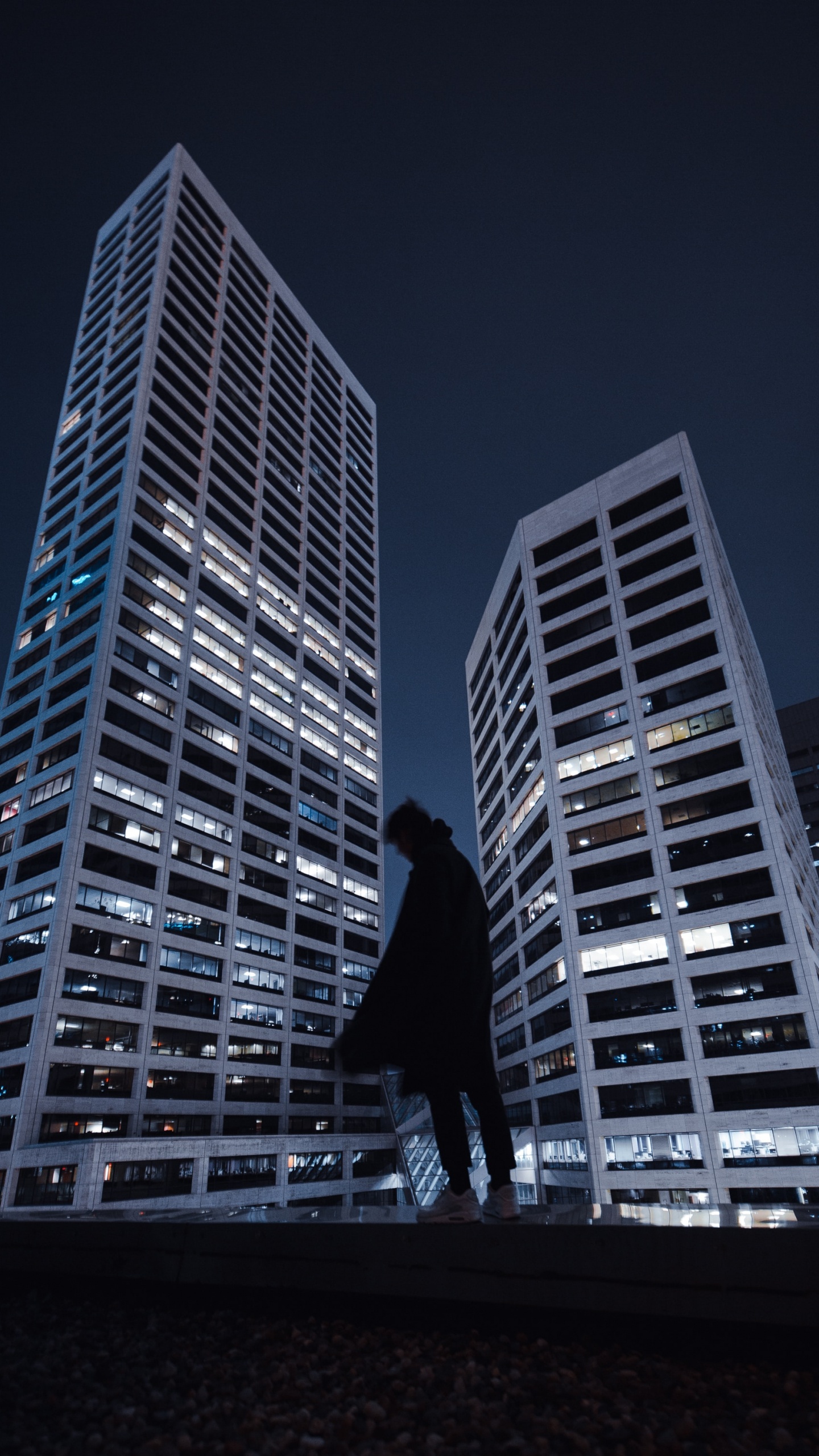 Mann in Schwarzer Jacke Und Hose, Der Nachts Vor Einem Hochhaus Steht. Wallpaper in 1440x2560 Resolution