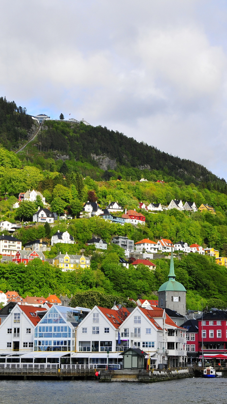 White and Brown Houses Near Green Mountain Under White Clouds During Daytime. Wallpaper in 750x1334 Resolution