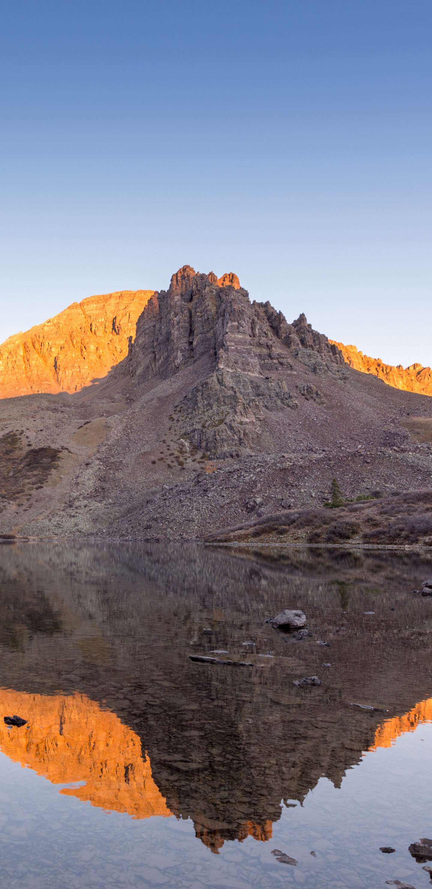 Brown Rocky Mountain Beside Body of Water During Daytime. Wallpaper in 1440x2960 Resolution