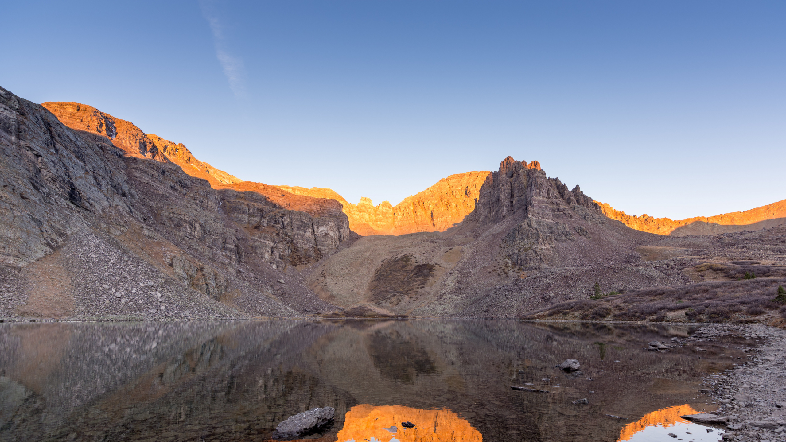 Brown Rocky Mountain Beside Body of Water During Daytime. Wallpaper in 2560x1440 Resolution