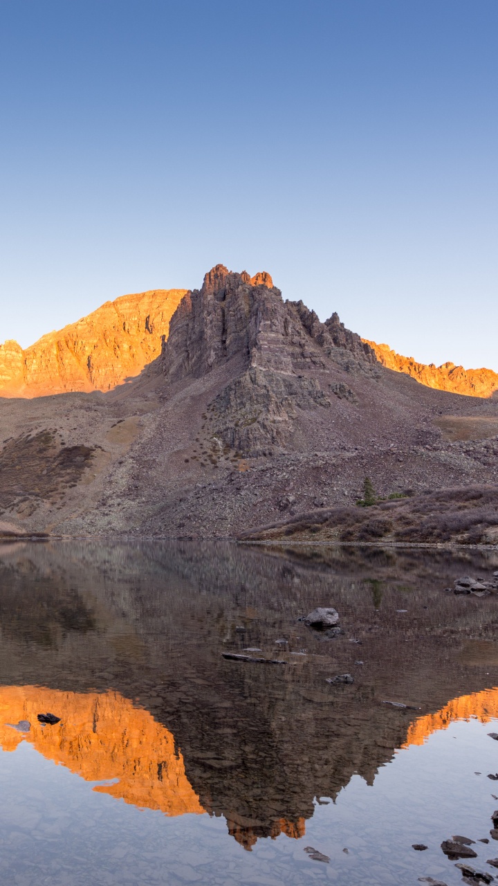 Brown Rocky Mountain Beside Body of Water During Daytime. Wallpaper in 720x1280 Resolution