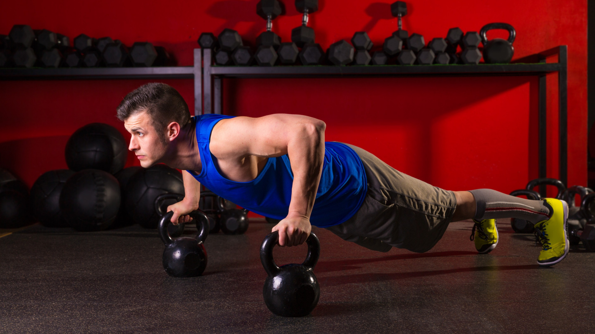 Man in Blue Tank Top and Black Shorts Holding Black Kettle Bell. Wallpaper in 1920x1080 Resolution