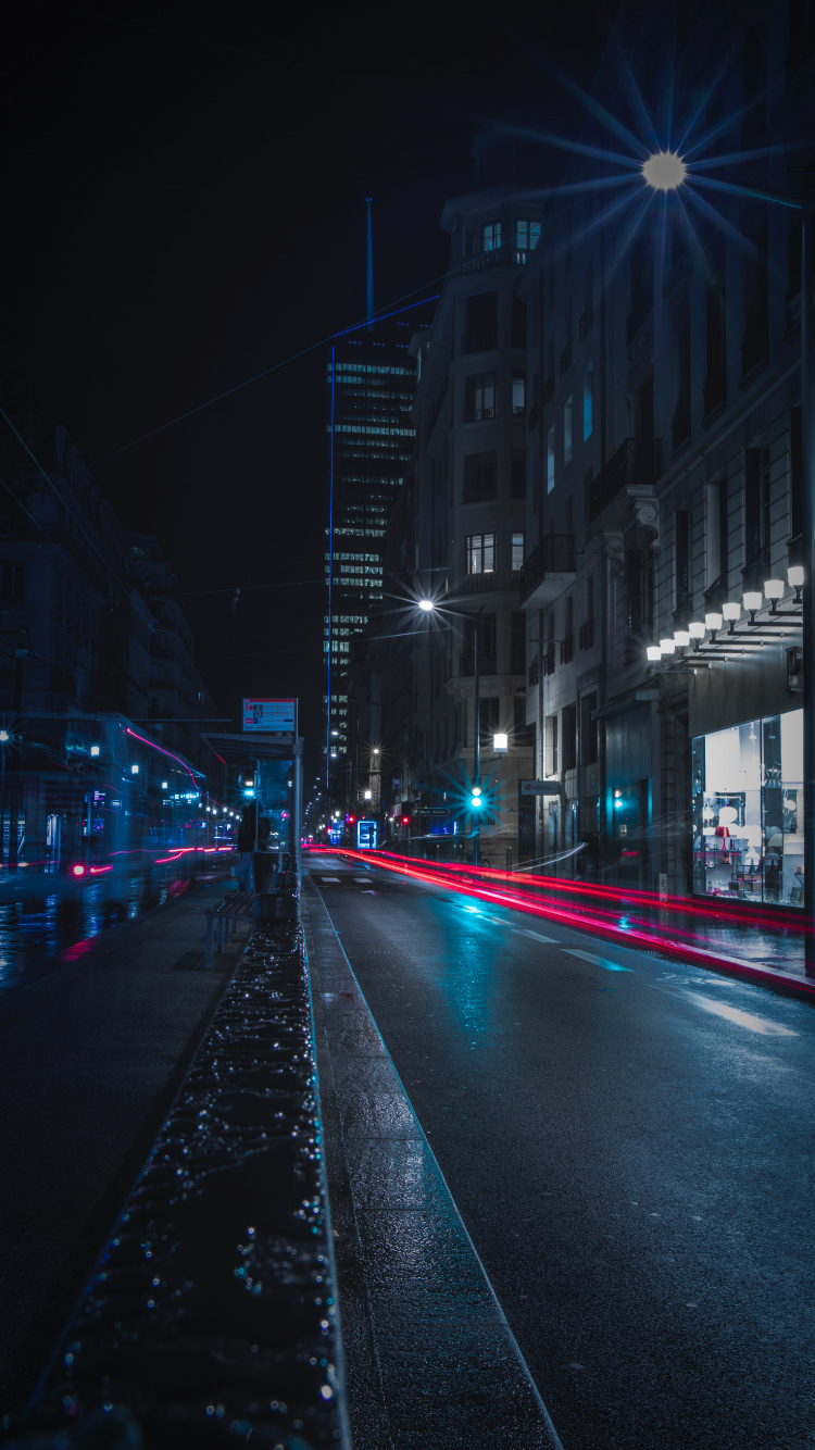 Coches en la Carretera Entre Edificios Durante la Noche. Wallpaper in 750x1334 Resolution