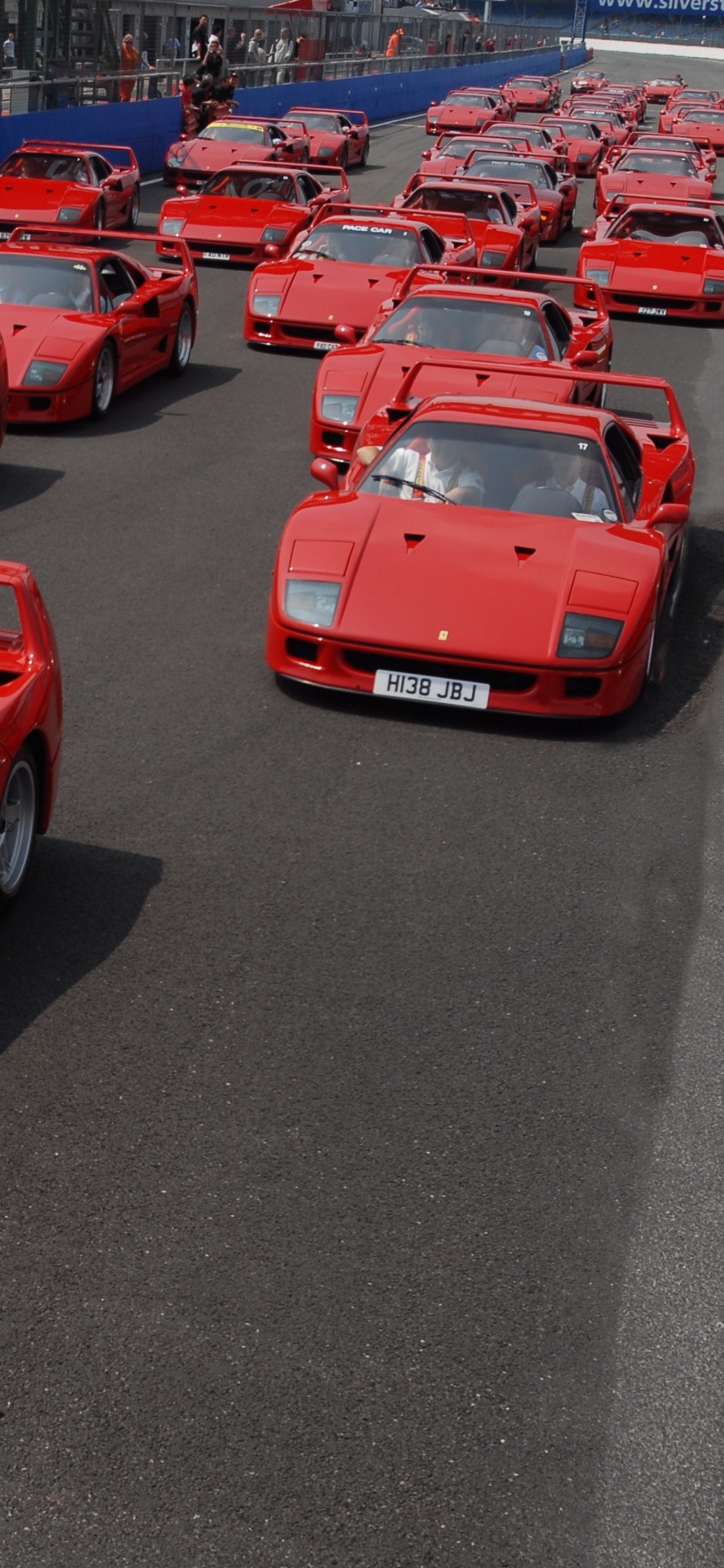 Voiture de Sport Ferrari Rouge Garée Sur un Parking Pendant la Journée. Wallpaper in 1125x2436 Resolution