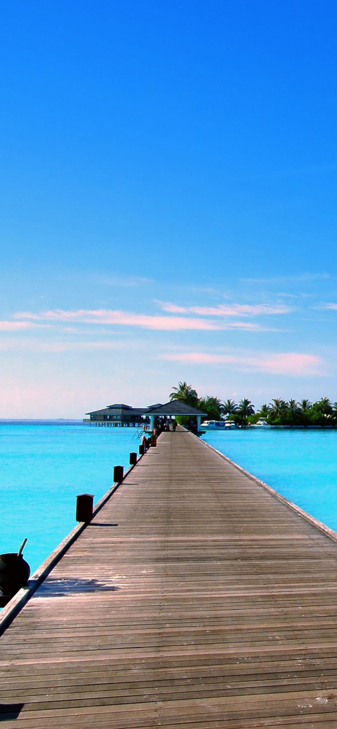 Braunes Holzdock Auf Blauem Meer Unter Blauem Himmel Tagsüber. Wallpaper in 1125x2436 Resolution