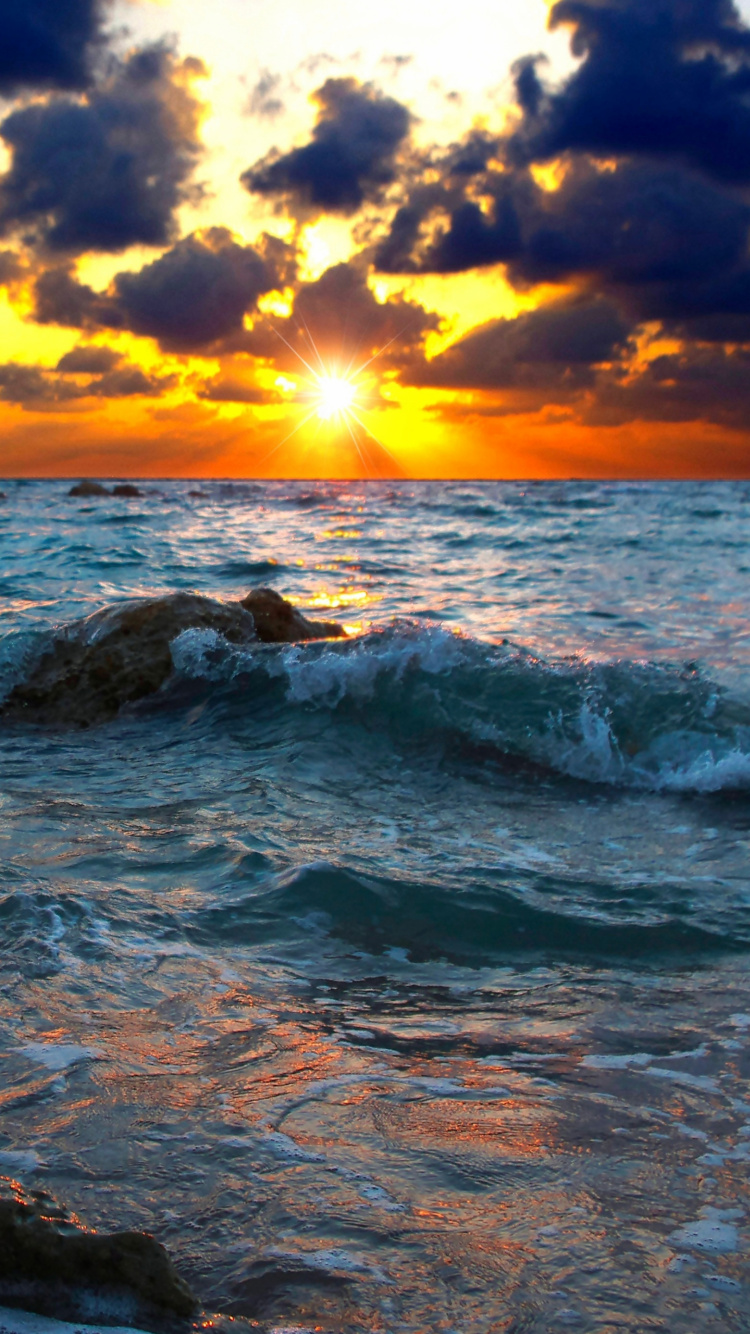 Rocky Shore Under Cloudy Sky During Sunset. Wallpaper in 750x1334 Resolution