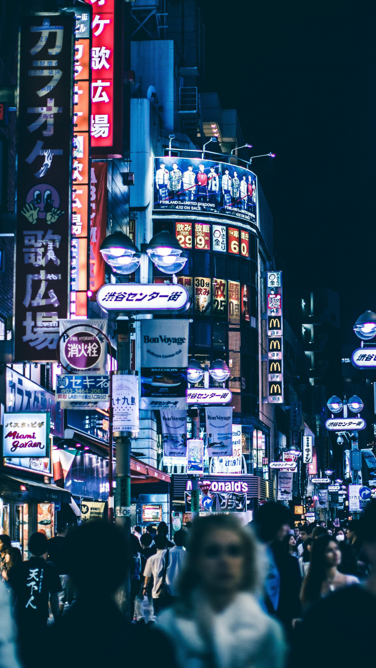 Leute, Die Nachts Auf Der Straße Gehen. Wallpaper in 750x1334 Resolution