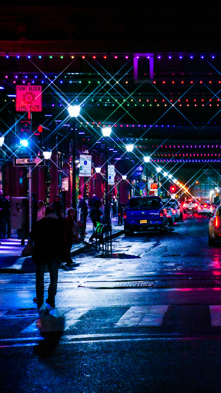 Gente Caminando en la Calle Durante la Noche. Wallpaper in 750x1334 Resolution