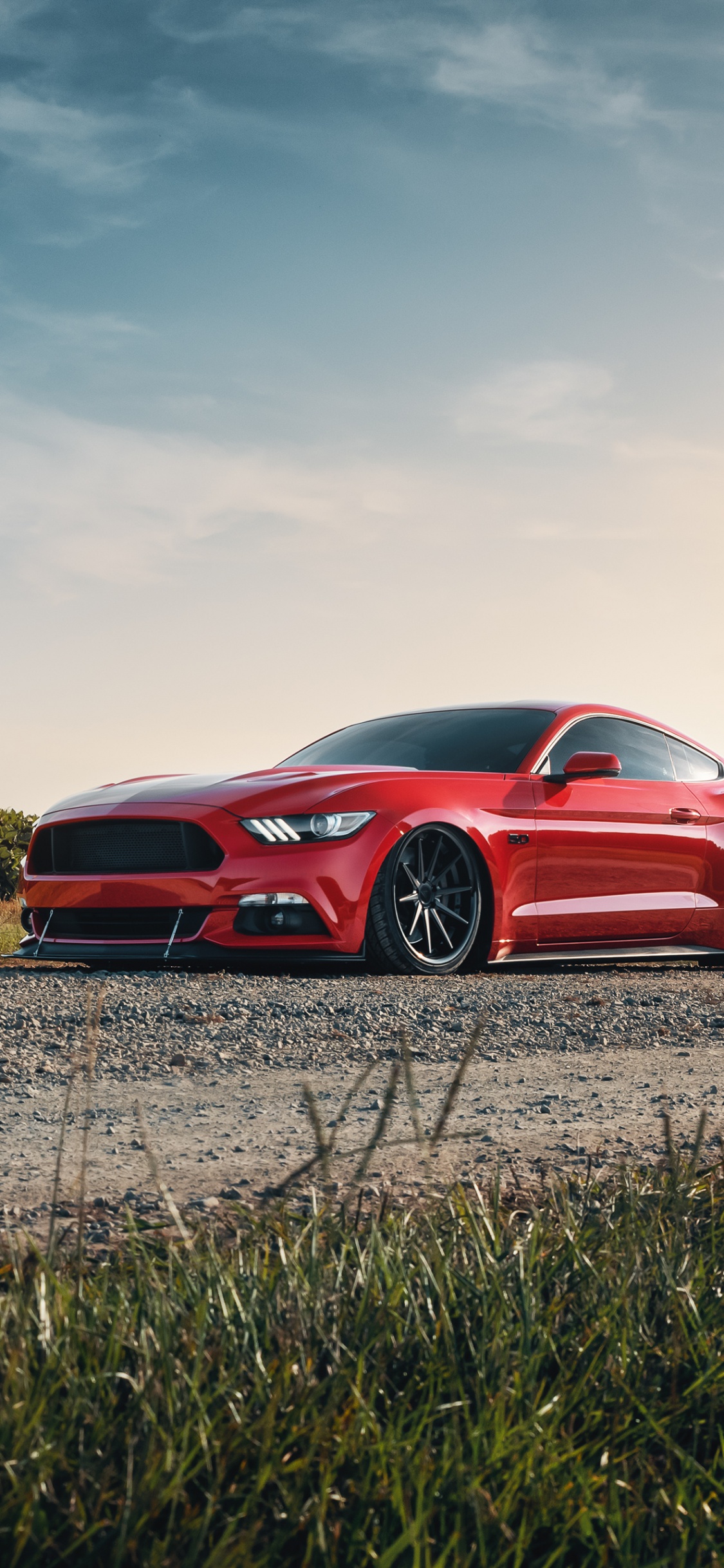 Red Chevrolet Camaro on Brown Grass Field Under White Clouds During Daytime. Wallpaper in 1125x2436 Resolution