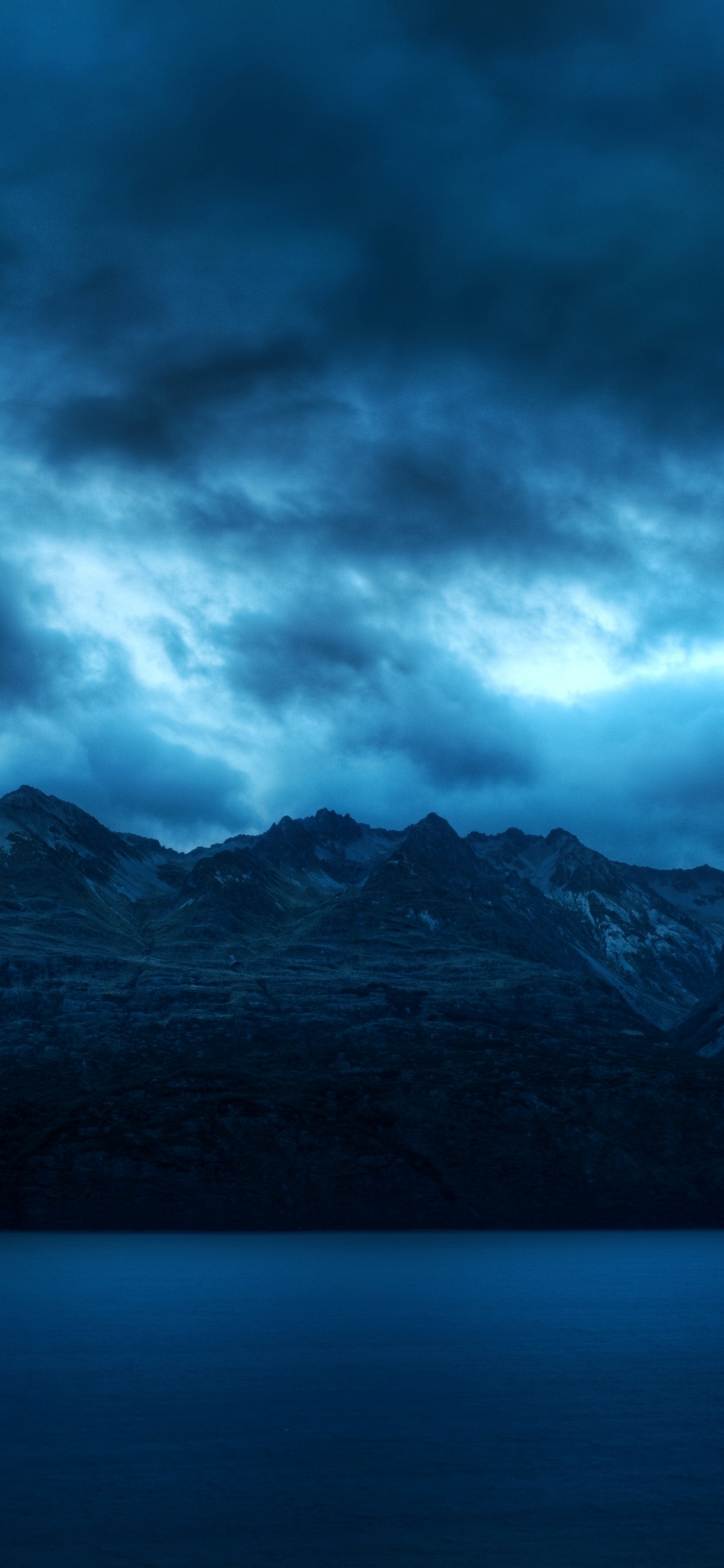 Black and White Mountains Under Gray Clouds. Wallpaper in 1125x2436 Resolution