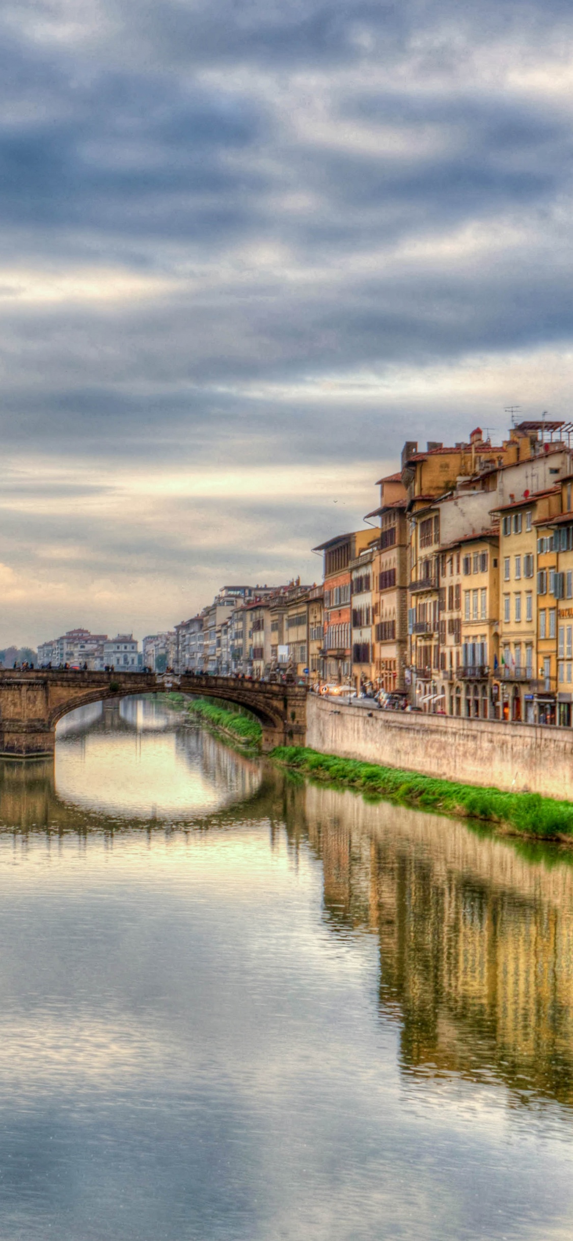 Braunes Betongebäude in Der Nähe Des Flusses Unter Bewölktem Himmel Tagsüber. Wallpaper in 1125x2436 Resolution