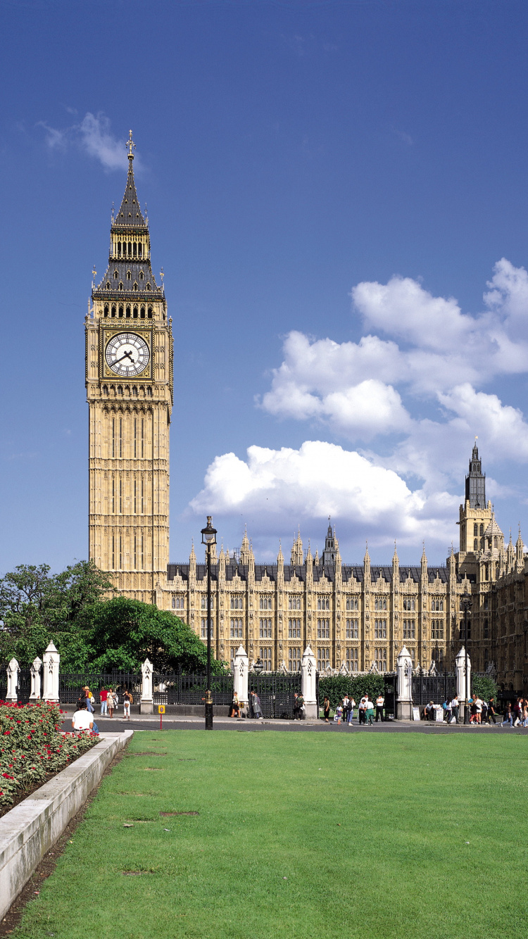 People Walking on Green Grass Field Near Brown Concrete Building During Daytime. Wallpaper in 750x1334 Resolution