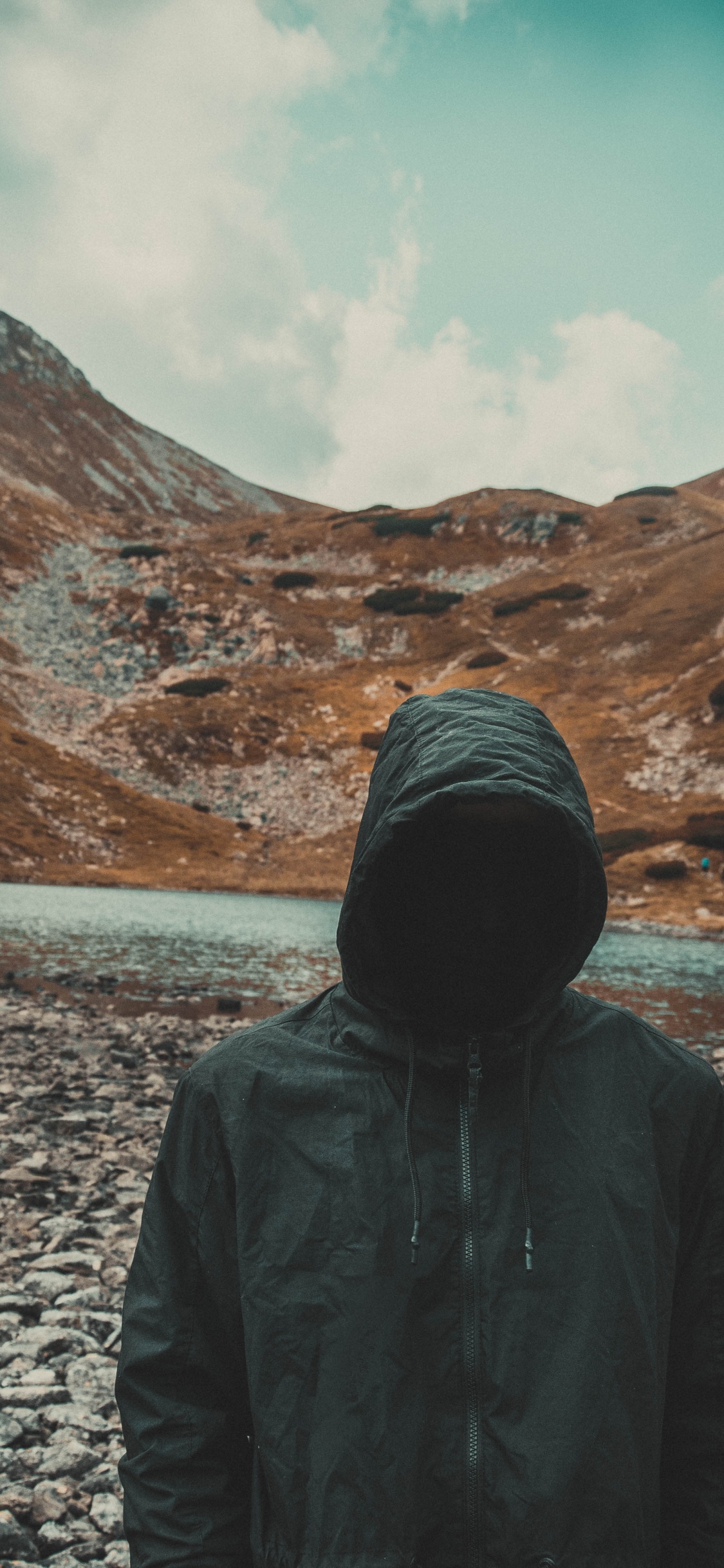 Person im Schwarzen Hoodie, Die Tagsüber Auf Grauem Felsigem Boden Steht. Wallpaper in 1125x2436 Resolution