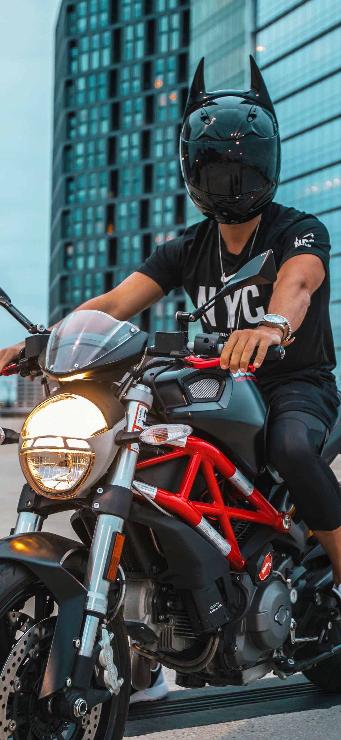 Mann Mit Schwarzem Helm, Der Auf Einem Orangefarbenen Und Schwarzen Motorrad Fährt. Wallpaper in 1125x2436 Resolution