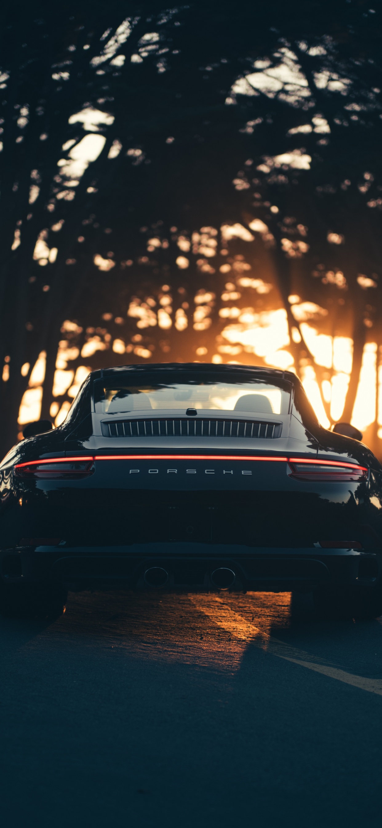 Coche Negro en la Carretera Durante la Puesta de Sol. Wallpaper in 1242x2688 Resolution