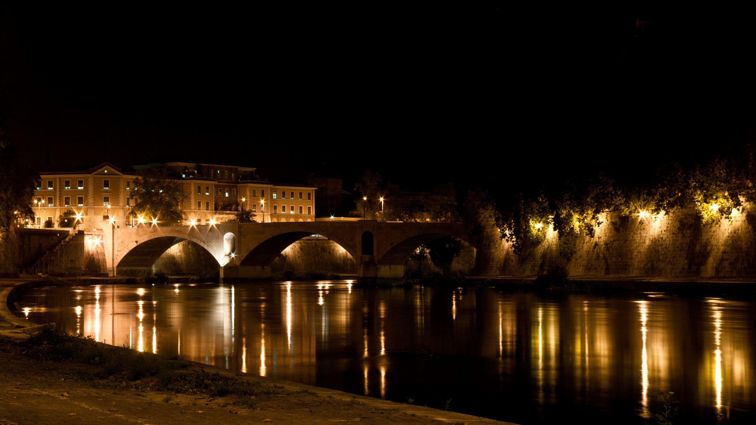 Edificio de Hormigón Marrón Cerca Del Cuerpo de Agua Durante la Noche. Wallpaper in 2560x1440 Resolution