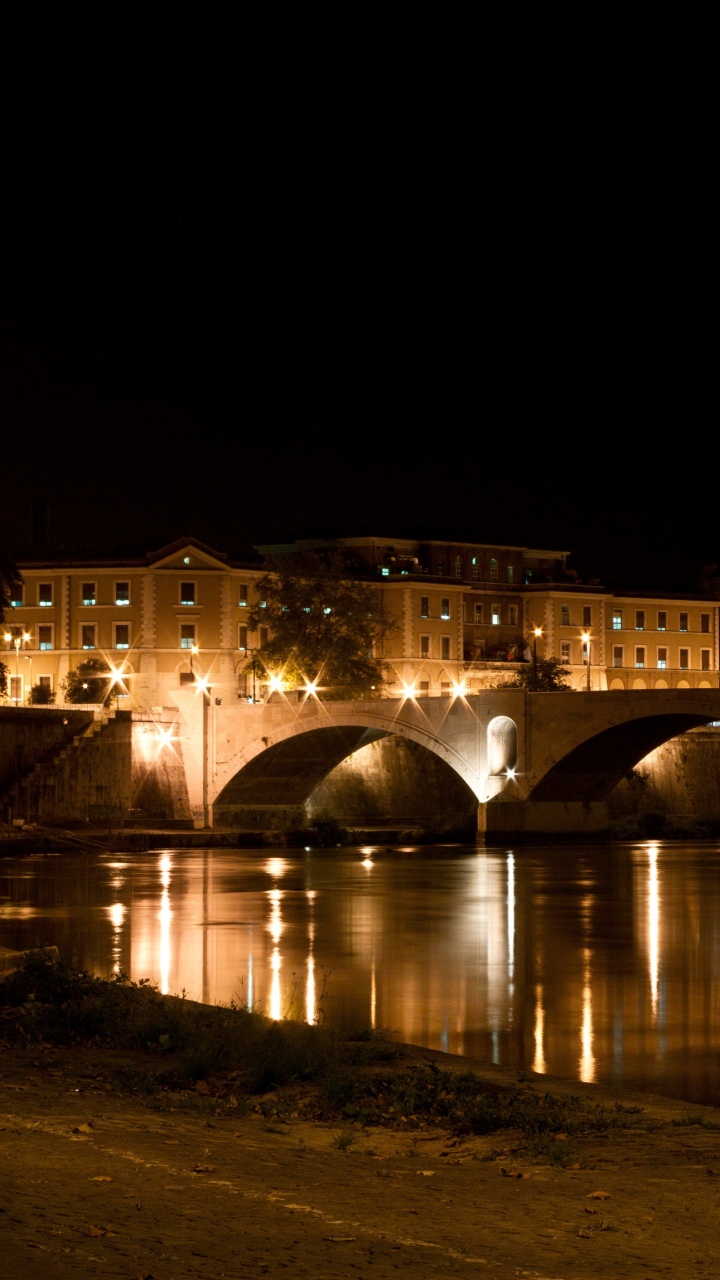 Edificio de Hormigón Marrón Cerca Del Cuerpo de Agua Durante la Noche. Wallpaper in 720x1280 Resolution