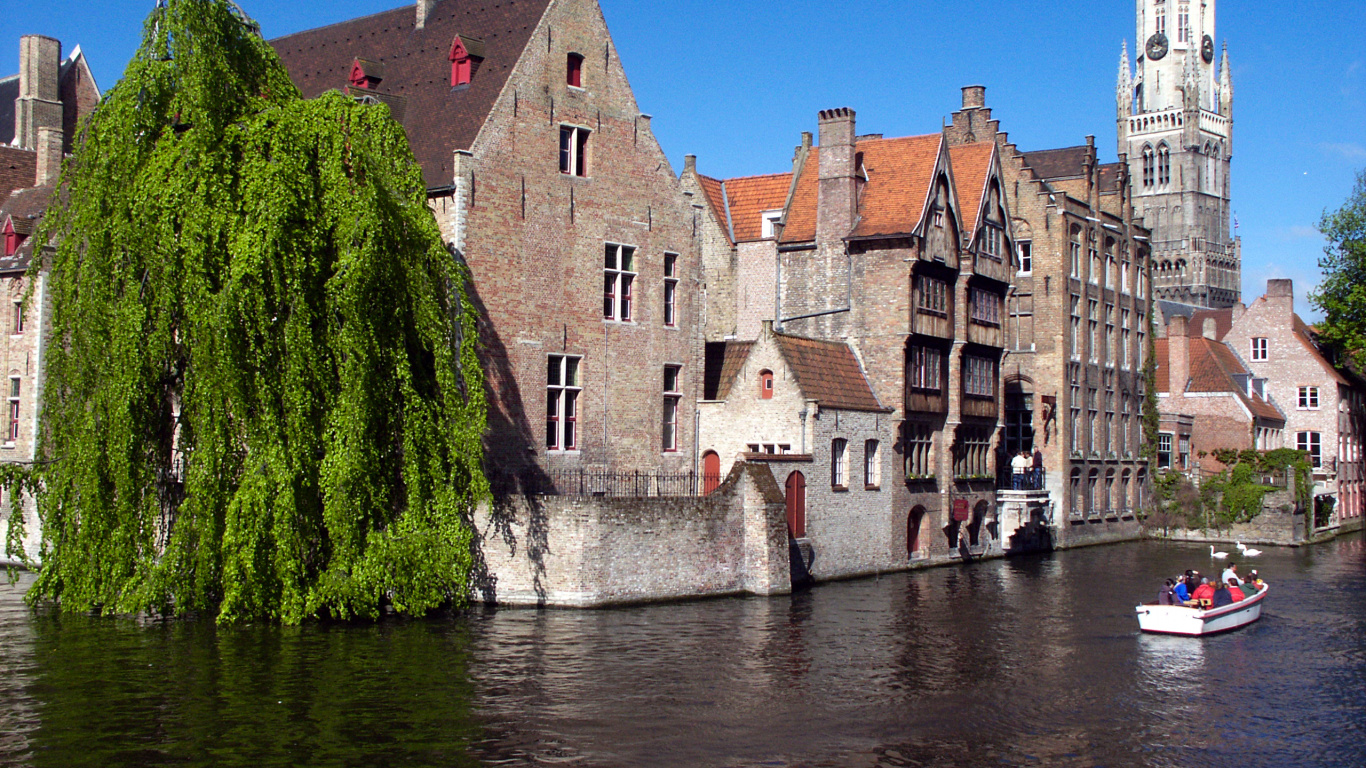 Brown Concrete Building Beside River During Daytime. Wallpaper in 1366x768 Resolution