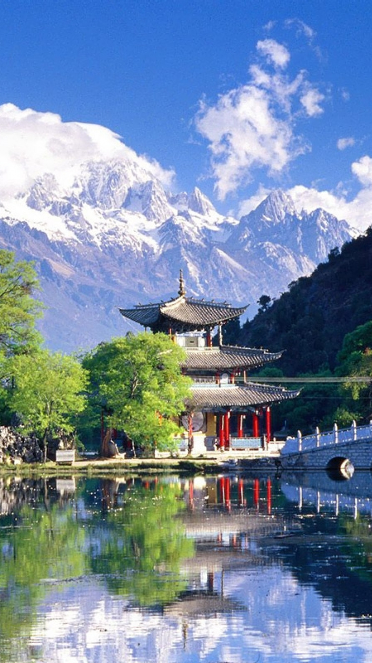 Puente de Madera Rojo y Blanco Sobre el Río Cerca de Árboles Verdes y Montañas Bajo un Cielo Azul y. Wallpaper in 750x1334 Resolution