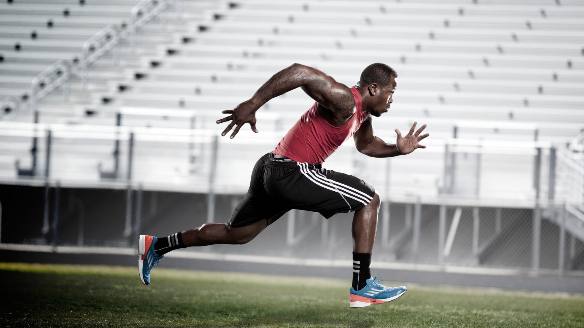 Man in Red Tank Top and Black Shorts Running on Green Grass Field During Daytime. Wallpaper in 1920x1080 Resolution