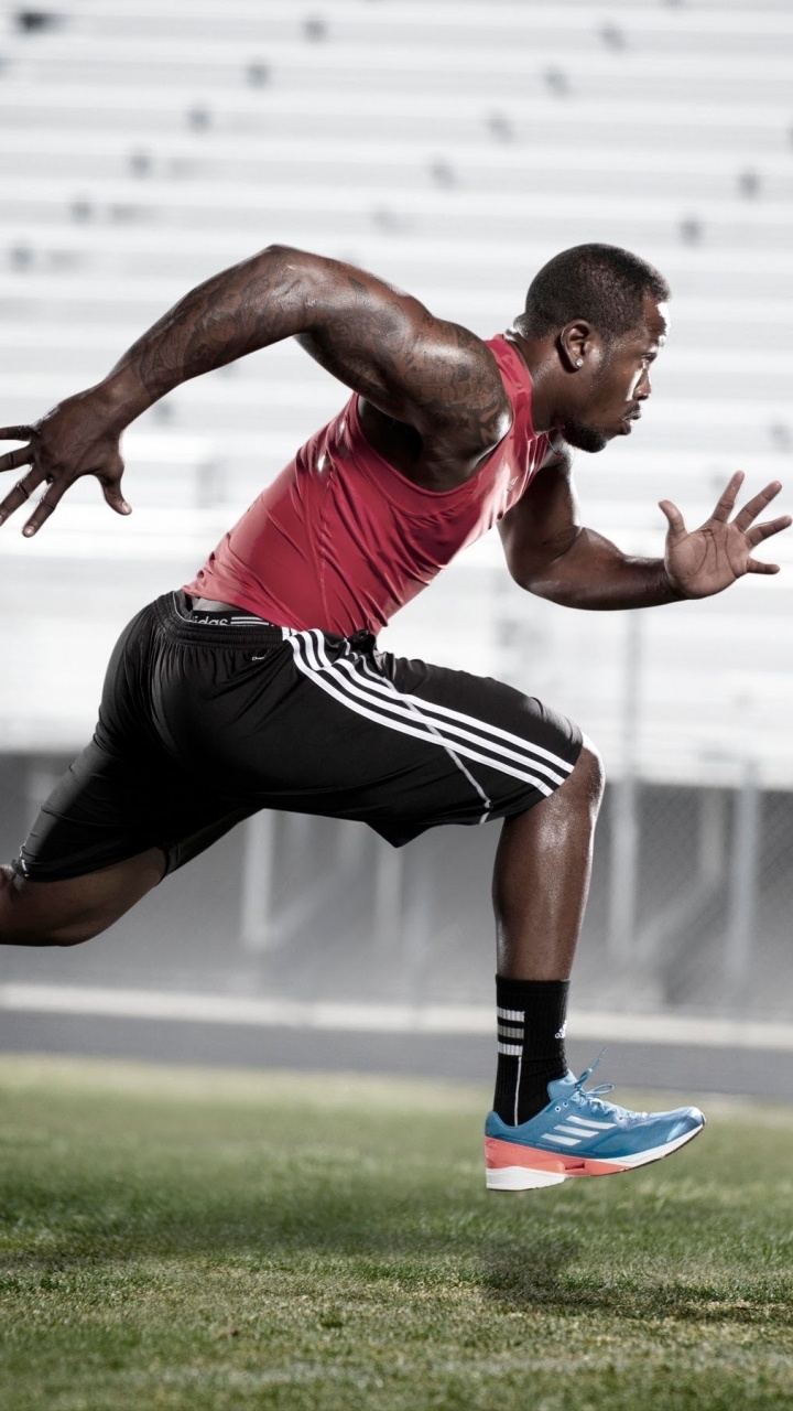 Man in Red Tank Top and Black Shorts Running on Green Grass Field During Daytime. Wallpaper in 720x1280 Resolution