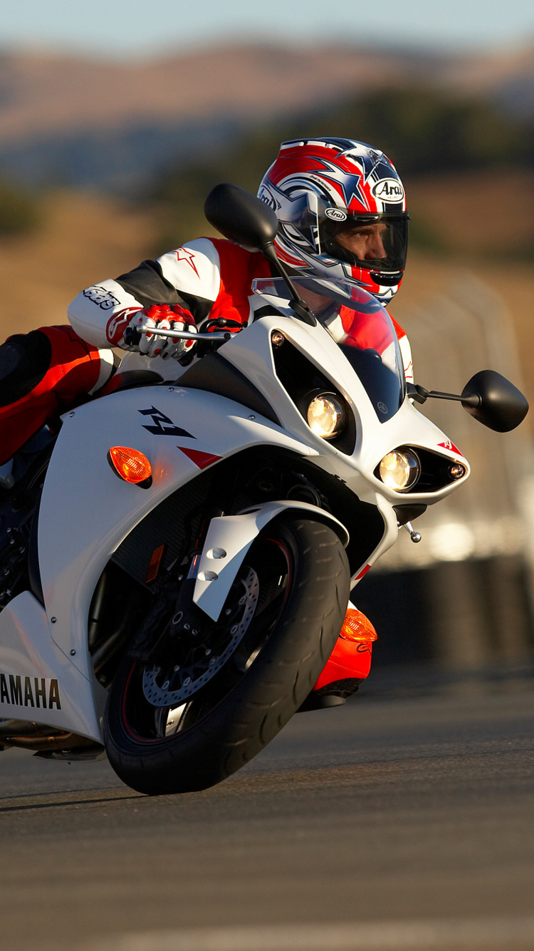 Mann im Schwarz-roten Motorradanzug, Der Auf Einem Weißen Und Schwarzen Sportmotorrad Fährt. Wallpaper in 750x1334 Resolution