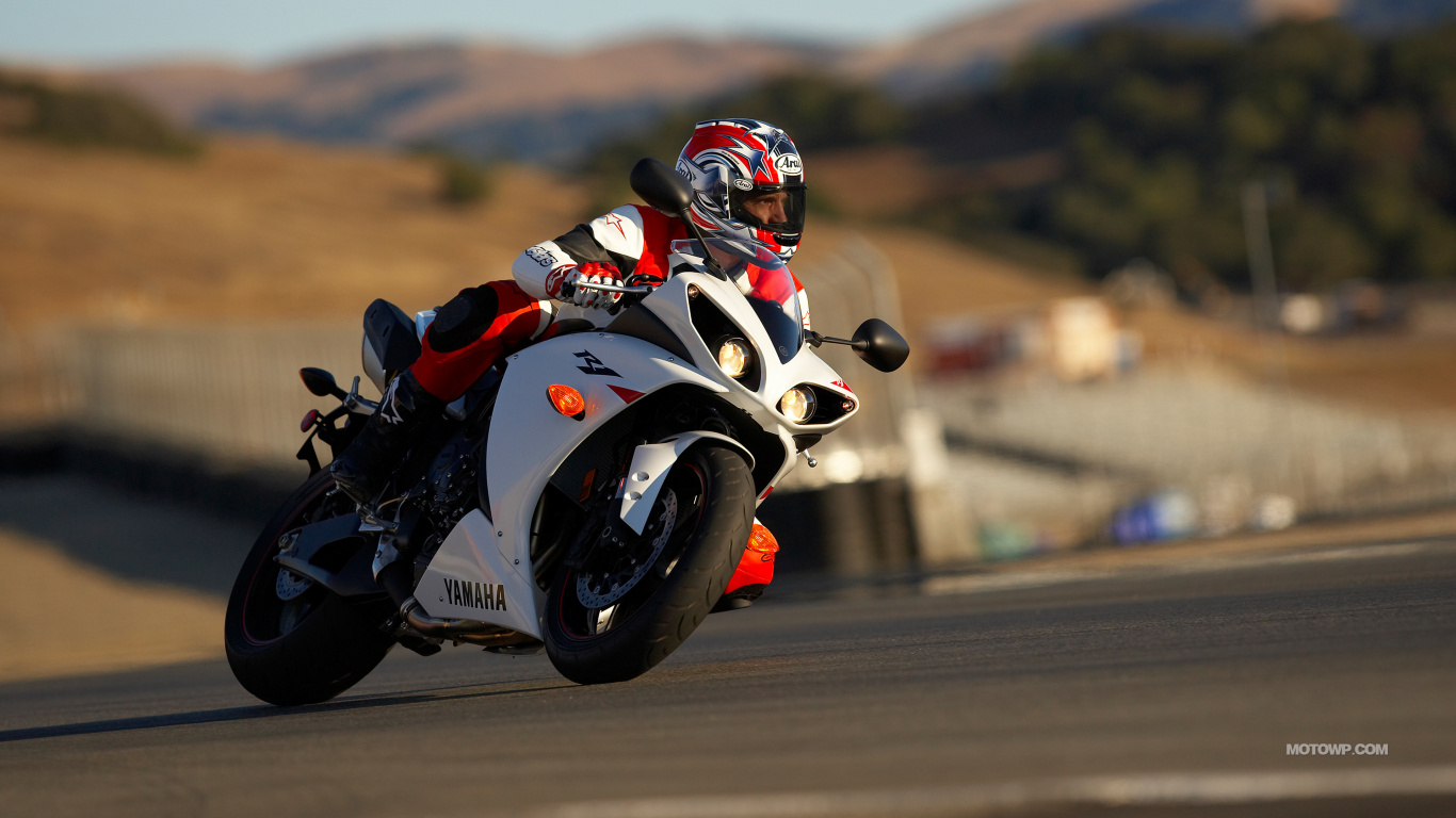 Man in Black and Red Motorcycle Suit Riding on White and Black Sports Bike. Wallpaper in 1366x768 Resolution