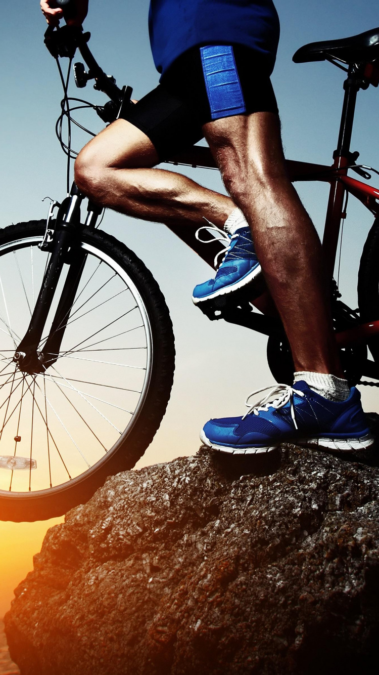 Hombre Con Camisa Azul Montando Bicicleta Negra Durante la Puesta de Sol. Wallpaper in 750x1334 Resolution