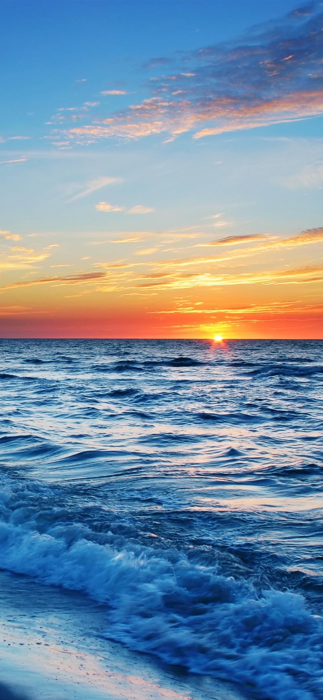 Ocean Waves Crashing on Shore During Sunset. Wallpaper in 1125x2436 Resolution
