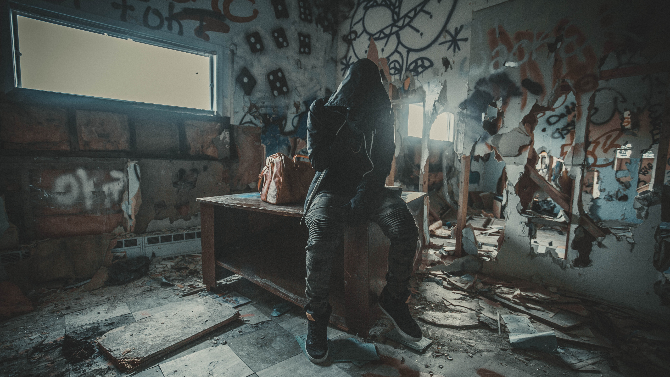 Man in Black Jacket Sitting on Brown Wooden Bench. Wallpaper in 2560x1440 Resolution