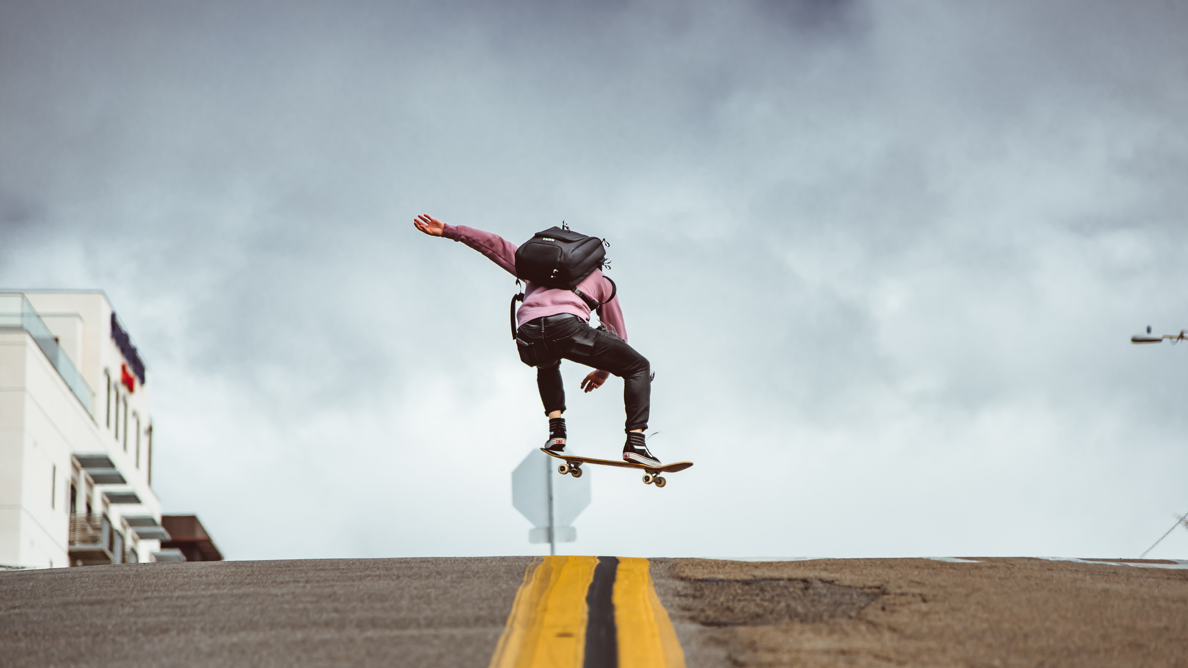 Man in Black Jacket and Black Pants Doing Stunts on Gray Asphalt Road Under Blue And. Wallpaper in 3840x2160 Resolution