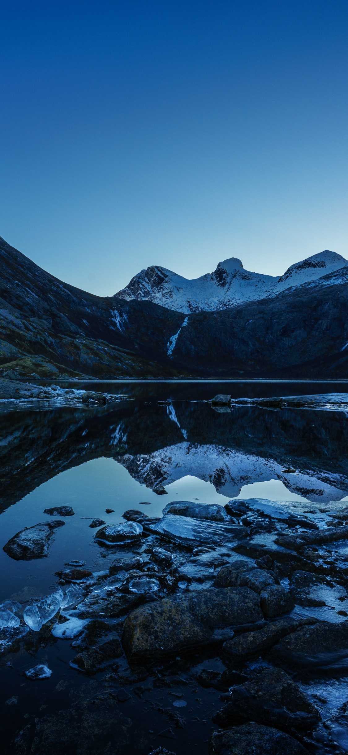 Snow Covered Mountain Near Body of Water During Daytime. Wallpaper in 1125x2436 Resolution