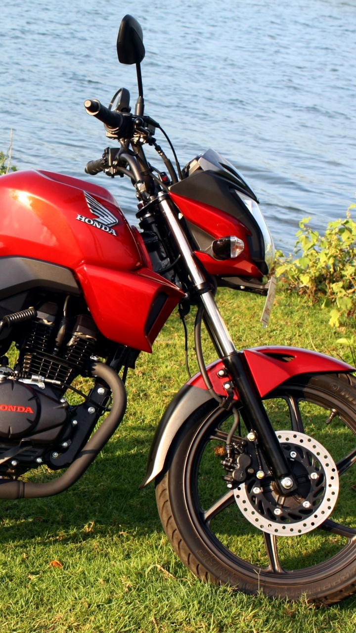 Red and Black Motorcycle on Green Grass Field Near Body of Water During Daytime. Wallpaper in 720x1280 Resolution