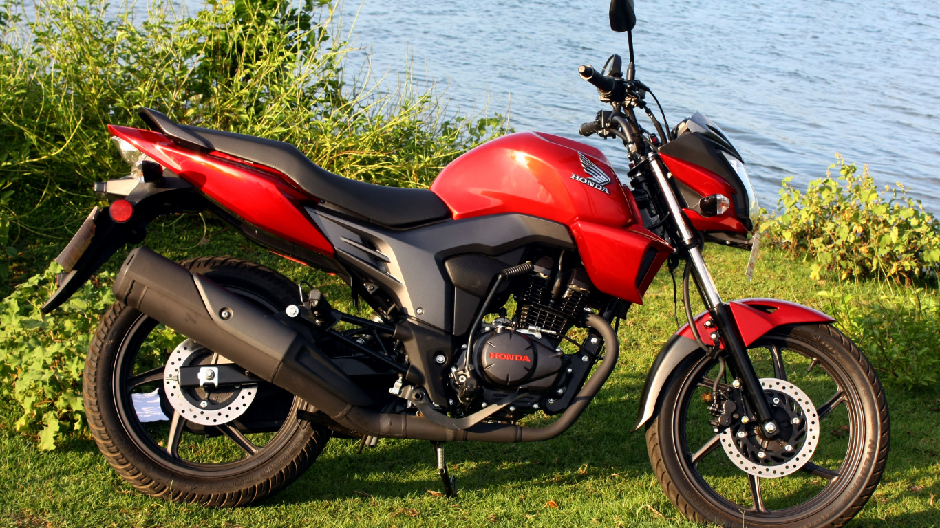 Rotes Und Schwarzes Motorrad Auf Grünem Grasfeld in Der Nähe Von Gewässern Tagsüber. Wallpaper in 1366x768 Resolution