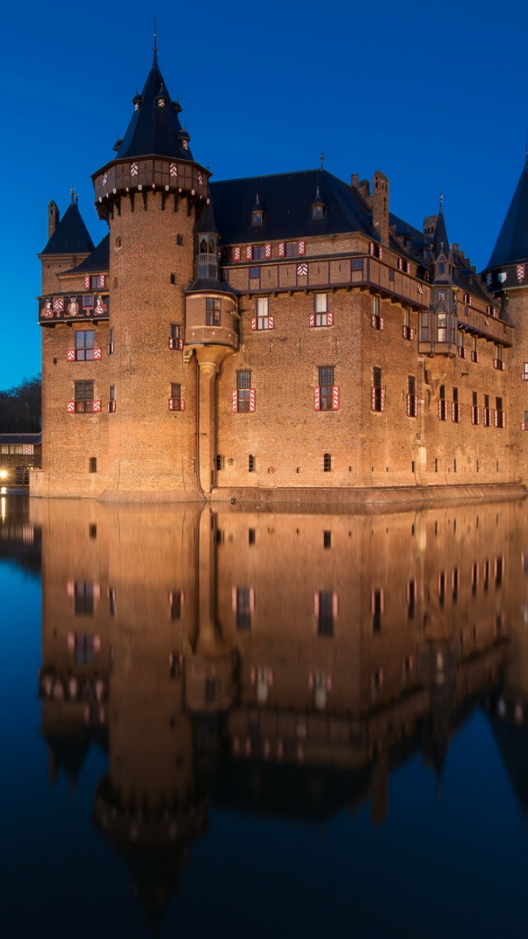 Château en Béton Brun Près D'un Plan D'eau Pendant la Nuit. Wallpaper in 750x1334 Resolution