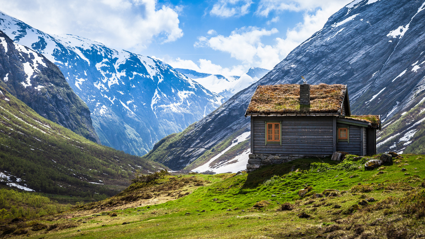 Maison en Bois Marron Sur Terrain D'herbe Verte Près Des Montagnes Couvertes de Neige Pendant la Journée. Wallpaper in 1366x768 Resolution