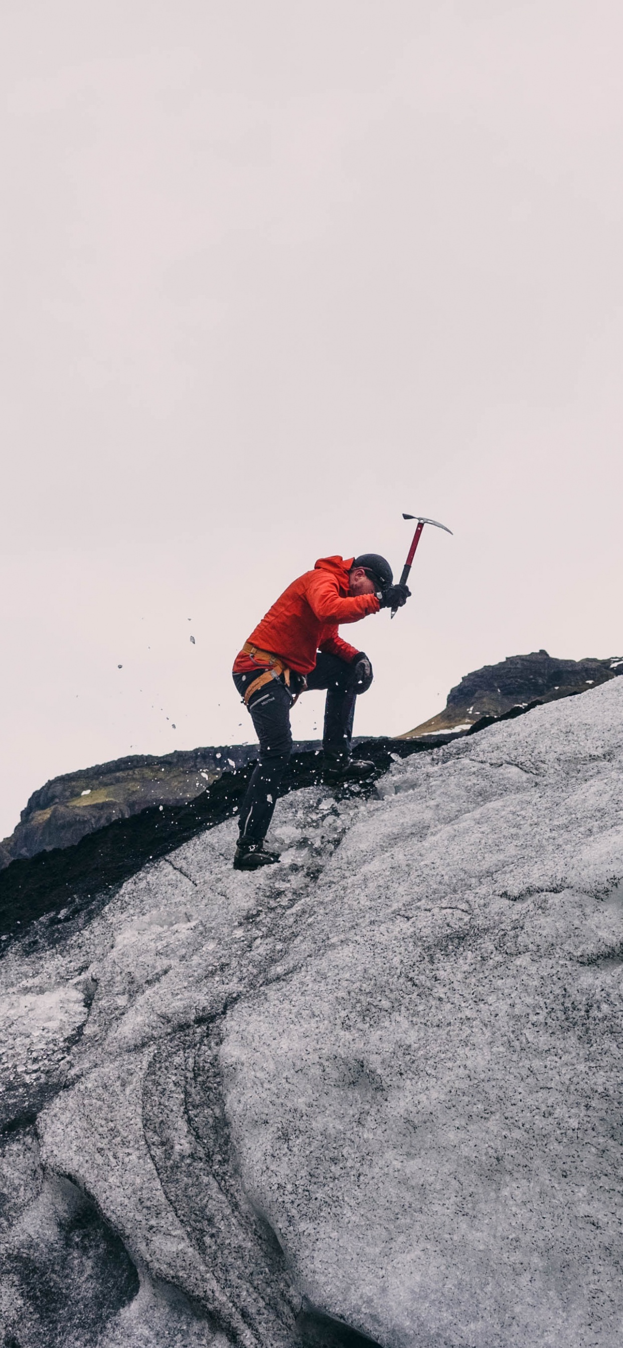 Person in Red Jacket and Black Pants Standing on Gray Rock Mountain During Daytime. Wallpaper in 1242x2688 Resolution