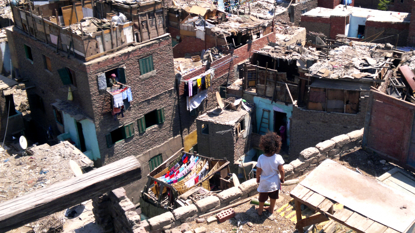 Man in White T-shirt and Blue Denim Jeans Standing on Brown Concrete Building During Daytime. Wallpaper in 1366x768 Resolution