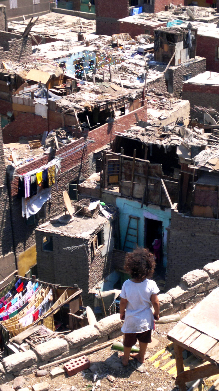 Homme en T-shirt Blanc et Jean Bleu Debout Sur un Bâtiment en Béton Marron Pendant la Journée. Wallpaper in 750x1334 Resolution